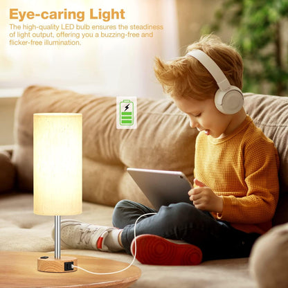 Child wearing headphones and using a tablet next to a small lamp on a table.