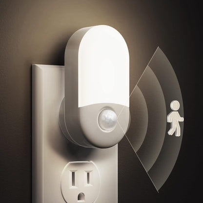 Infrared motion sensor light attached to a wall outlet with a dark background