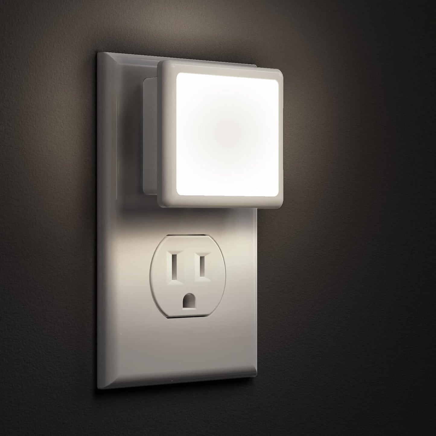 Night light attached to a wall outlet on a dark background