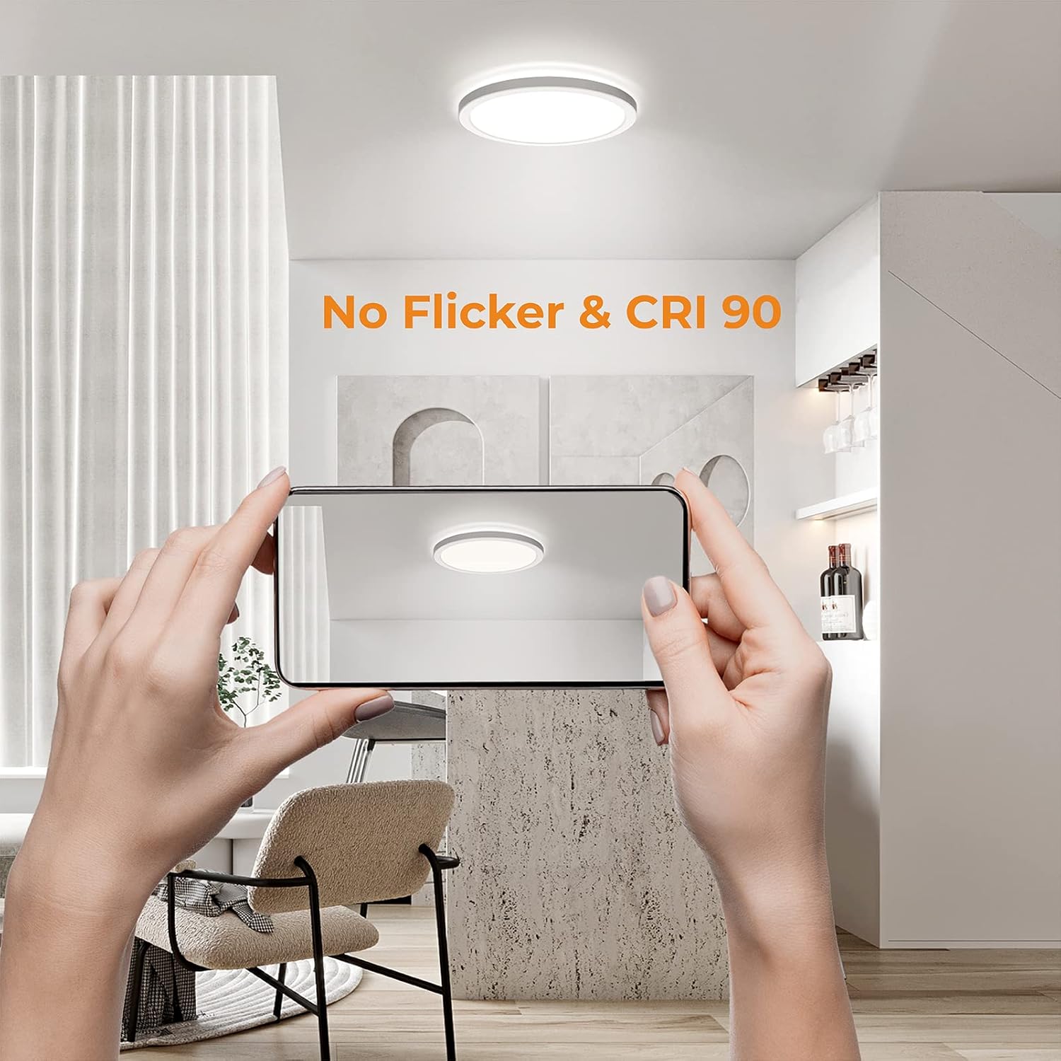 Person using a smartphone to take a photo of a ceiling light fixture in a modern kitchen.