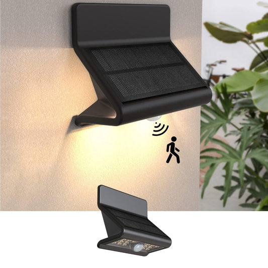 Solar-powered outdoor light fixture with motion sensor on a wall, next to a plant.