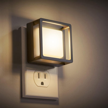 Square wall-mounted light fixture on a wall with an electrical outlet below.