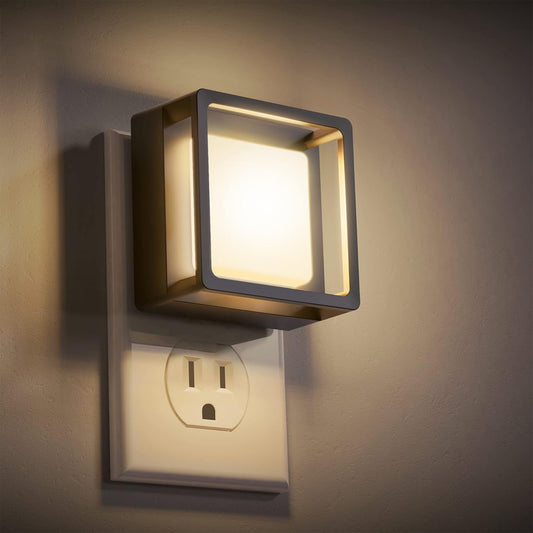 Square wall-mounted light fixture on a wall with an electrical outlet below.