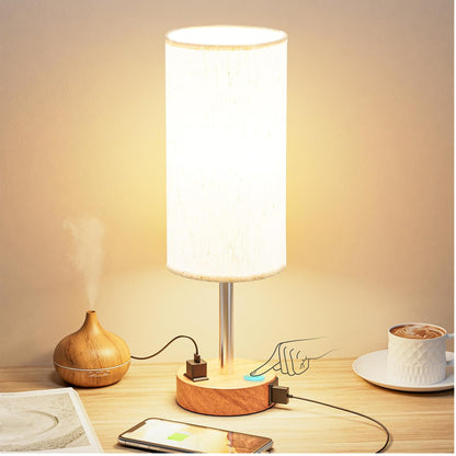 Table lamp with wooden base on a desk next to a cup of coffee and smartphone