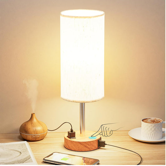Table lamp with wooden base on a desk next to a cup of coffee and smartphone