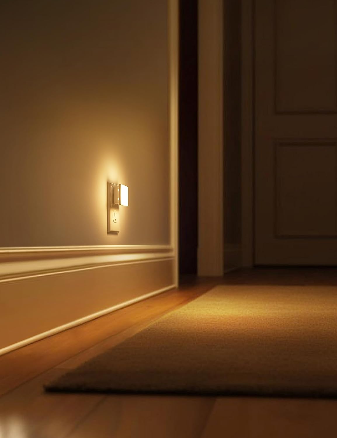 Wall-mounted light fixture casting a warm glow on a wall and floor in a dimly lit room.
