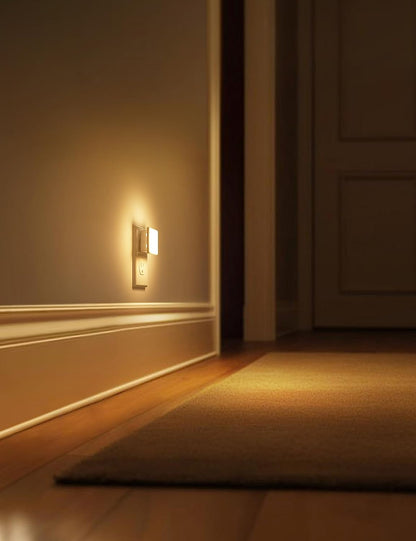 Wall-mounted light fixture casting a warm glow on a wall and floor in a dimly lit room.