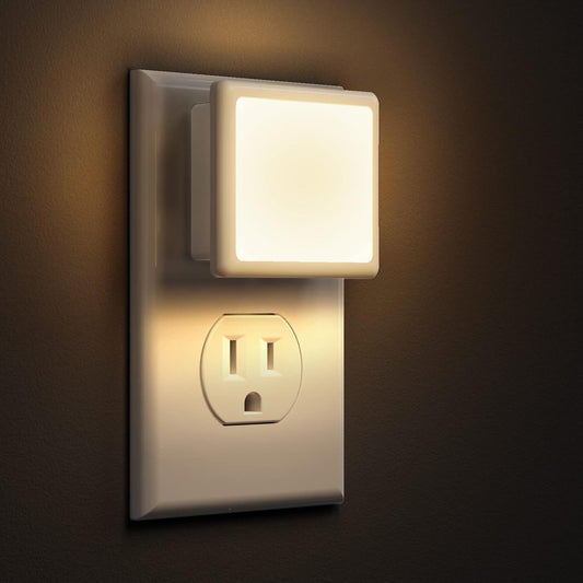 Wall-mounted night light attached to a standard electrical outlet on a dark background